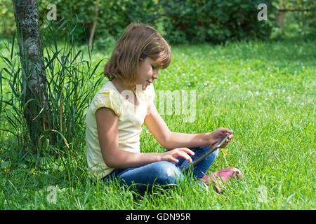 Fille dans le jardin avec la tablette Banque D'Images