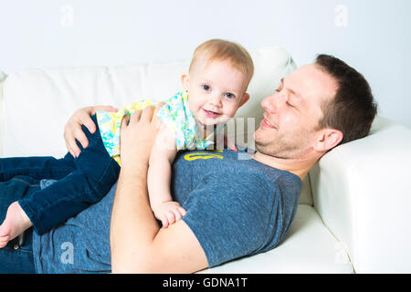 Père avec bébé sur le canapé en prenant du bon temps Banque D'Images