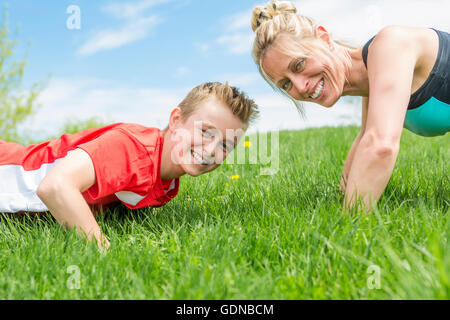 Mère et fils sont heureux de faire les exercices dans le parc d'été Banque D'Images