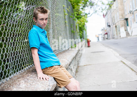 Young teen garçon à la recherche d'une clôture Banque D'Images