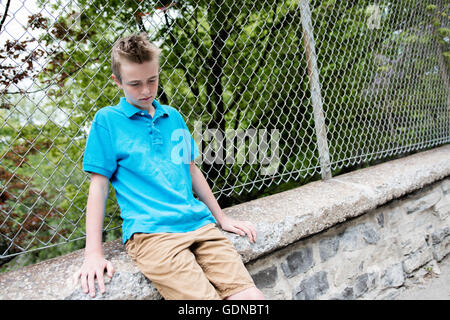 Young teen garçon à la recherche d'une clôture Banque D'Images
