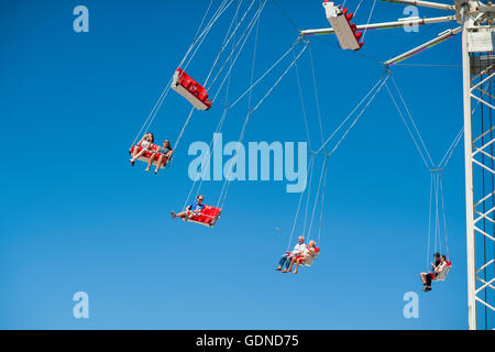Personnes sur parc d'ride balançoires dans les airs avec fond de ciel bleu Banque D'Images