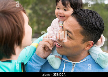 Couple playing piggyback ride with baby in park Banque D'Images