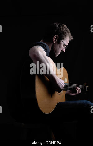 Touche Bas shot of mid adult man playing guitar Banque D'Images