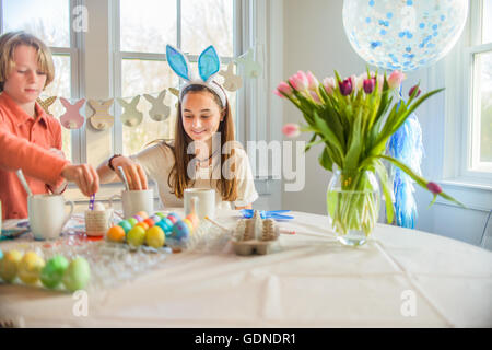 Adolescente et frère de la teinture des œufs durs pour Pâques à table Banque D'Images