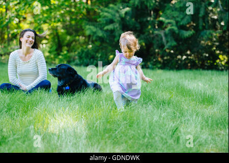 Female toddler courir loin de mère en park Banque D'Images