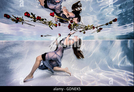Woman wearing dress sous l'eau à la piscine avec des roses Banque D'Images