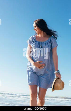 Femme enceinte marche sur la plage Banque D'Images