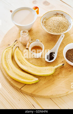 Petit-déjeuner sain avec les bananes, le miel, le lait de coco et les matières en poudre Banque D'Images