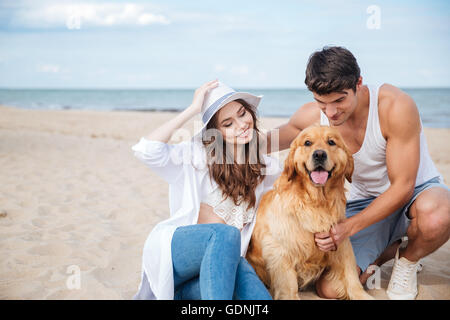 Belle jeune couple aimant jouer avec leur chien au bord de la mer Banque D'Images