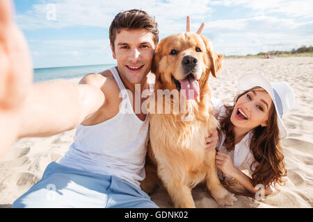 Jeune couple heureux avec un chien à la plage selfies Banque D'Images