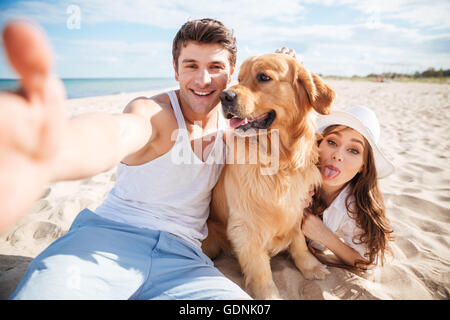 Jeune couple heureux avec un chien à la plage selfies Banque D'Images