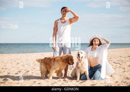 Young beautiful couple debout sur le bord de la mer avec chien Banque D'Images