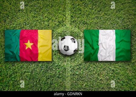 Cameroun contre le Nigeria les drapeaux sur le terrain de soccer vert Banque D'Images