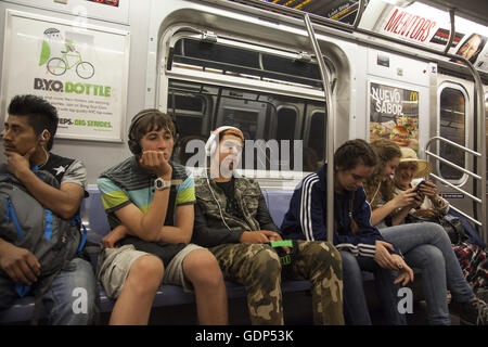 Les jeunes, mais jusqu'à présent à part à l'écoute de leurs appareils électroniques. New York City Subway train. Banque D'Images