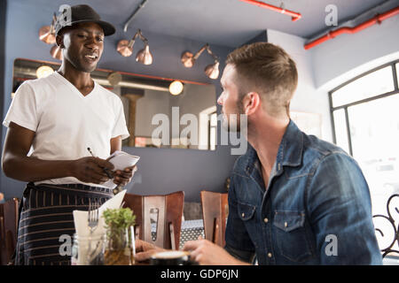 Serveur dans un restaurant prenant clients commande Banque D'Images