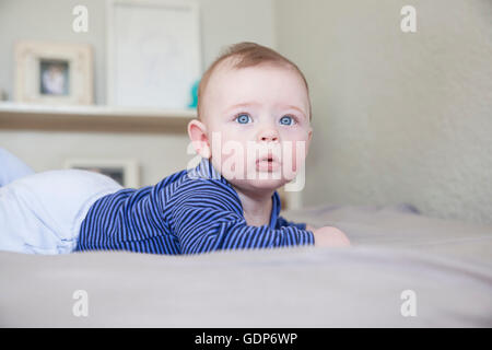 Portrait de blue eyed baby boy lying on bed Banque D'Images