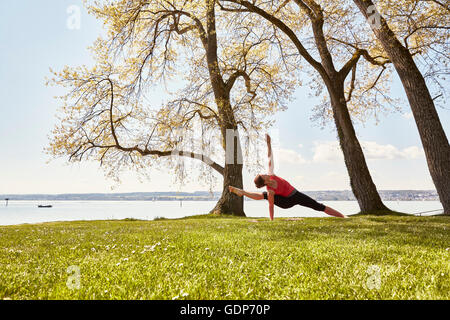 Femme avec bras et jambe soulevée in yoga position Banque D'Images