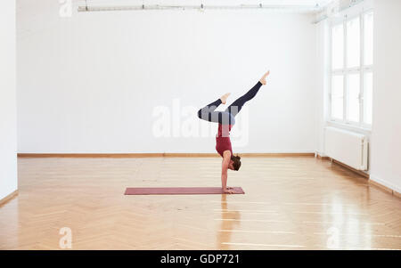 Side view of woman in studio exercice doing handstand Banque D'Images