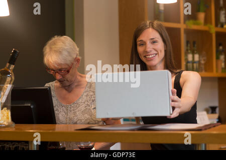 Vendeur en magasin de vin holding box looking at camera smiling Banque D'Images