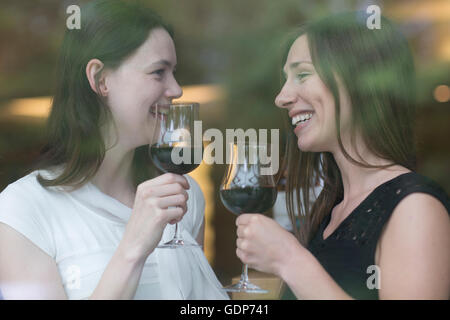 Fenêtre vue par des jeunes femmes tenant des verres à vin face à face smiling Banque D'Images