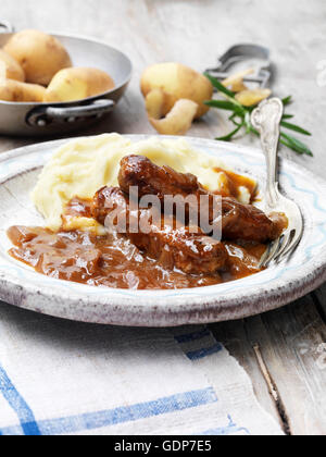 La nourriture végétarienne) saucisse végétarienne sauce oignon purée de pommes de tonnerres rosemary vintage bol table rustique en bois Banque D'Images