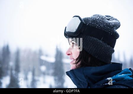 Portrait de jeune femme portant des lunettes de ski à regarder la neige, station de ski de Brighton en dehors de Salt Lake City, Utah, USA Banque D'Images