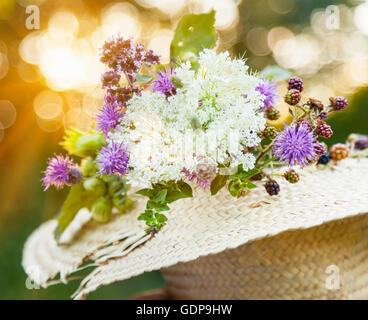 Fleurs sauvages fraîchement cueillis à la noisette in straw hat Banque D'Images