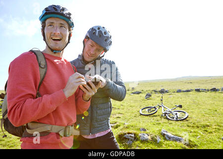 Les cyclistes sur hillside looking at smartphone Banque D'Images