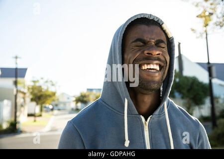 Portrait of man wearing hooded top les yeux fermés riant Banque D'Images