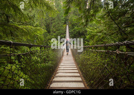 Femme sur le pont suspendu de Lynn canyon, North Vancouver, Colombie-Britannique, Canada Banque D'Images