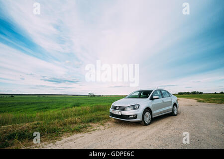 Gomel, Bélarus - 13 juin, 2016 : Volkswagen Polo Parking voiture sur l'accotement des routes de campagne, sur fond de champs de printemps vert Banque D'Images