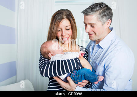 Les fiers parents Holding Baby dans la chambre à coucher Banque D'Images
