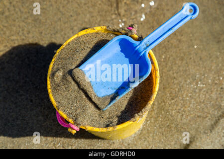 Toy Spade et godet sur une plage de sable. Banque D'Images