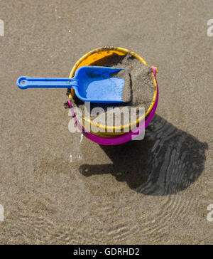 Toy Spade et godet sur une plage de sable. Banque D'Images