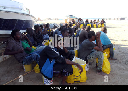 Tripoli. 21 juillet, 2016. Les migrants illégaux s'asseoir sur le quai de port de Tripoli Tripoli (Libye) le 21 juillet 2016. Quelque 137 migrants d'origine africaine ont été secourus par deux bateaux de la garde côtière en mer lorsque leur bateau a commencé naufrage au large de la côte libyenne. Credit : Hamza Turkia/Xinhua/Alamy Live News Banque D'Images