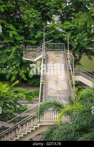 Vieux pont en béton avec paroi en acier inoxydable et d'un lampadaire au-dessus de la petite route locale entouré d'arbre vert sur deux côtés. Banque D'Images
