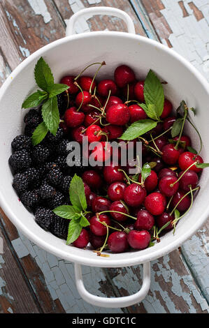 Les fruits d'été dans une passoire sur une vieille table Banque D'Images