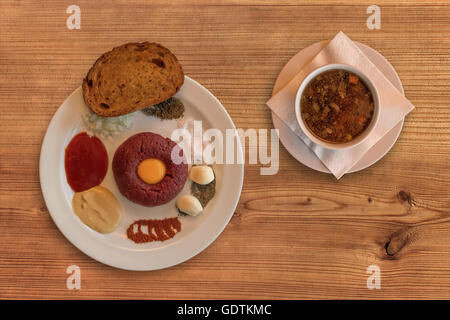 Mise à plat de bœuf cru . Délicieux Steak tartare. Steak tartare classique sur table en bois rustique avec un bouillon de boeuf. Ingrédients : matières bee Banque D'Images