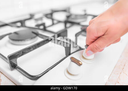 La main féminine comprend une cuisinière à gaz. Close-up. Banque D'Images