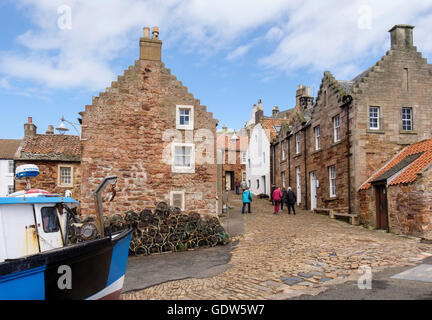 Vieux cottages près du port avec des visiteurs marchant sur une rue pavée dans le village de pêche de Firth of Forth. Rail East Neuk Fife Fife Ecosse Royaume-Uni Grande-Bretagne Banque D'Images