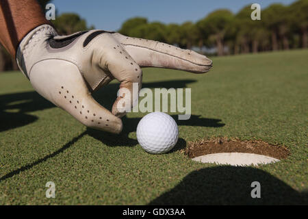 Close up of man's hand putting balle de golf dans le trou en cours Banque D'Images