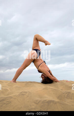 Jeune femme pratiquant le yoga dans le désert de sable Banque D'Images