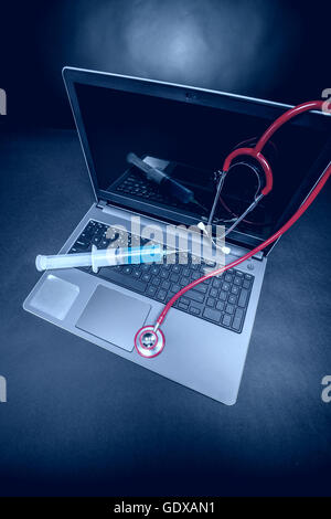 Ordinateur portable avec un stéthoscope et seringue hypodermique sur fond bleu Banque D'Images