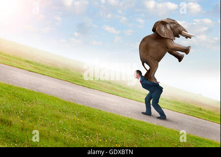 Concept d'adversité avec businessman carrying elephant uphill Banque D'Images