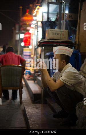 Les jeunes Chinois jouent avec leurs smartphones et les médias sociaux, à Beijing, Chine Banque D'Images