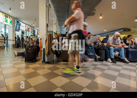 Passagers en salle d'embarquement à l'aéroport Galileo Galilei en attente de leur vol, Pise, Toscane, Italie Banque D'Images