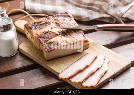 Tranches de lard fumé sur table en bois. Banque D'Images