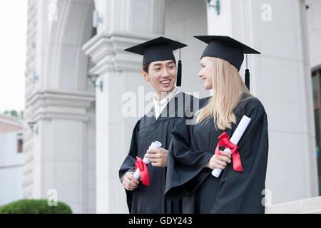 Vue de côté portrait de deux diplômés de collège souriant face à face Banque D'Images