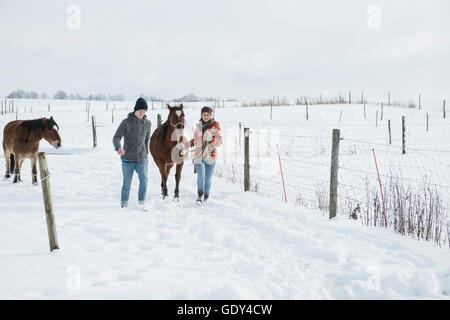 Jeune couple en train de marcher avec les chevaux dans le champ, Bavière, Allemagne Banque D'Images